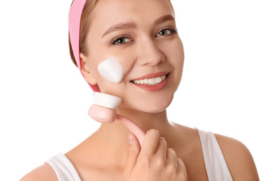 Photo of Young woman washing face with brush and cleansing foam on white background. Cosmetic products