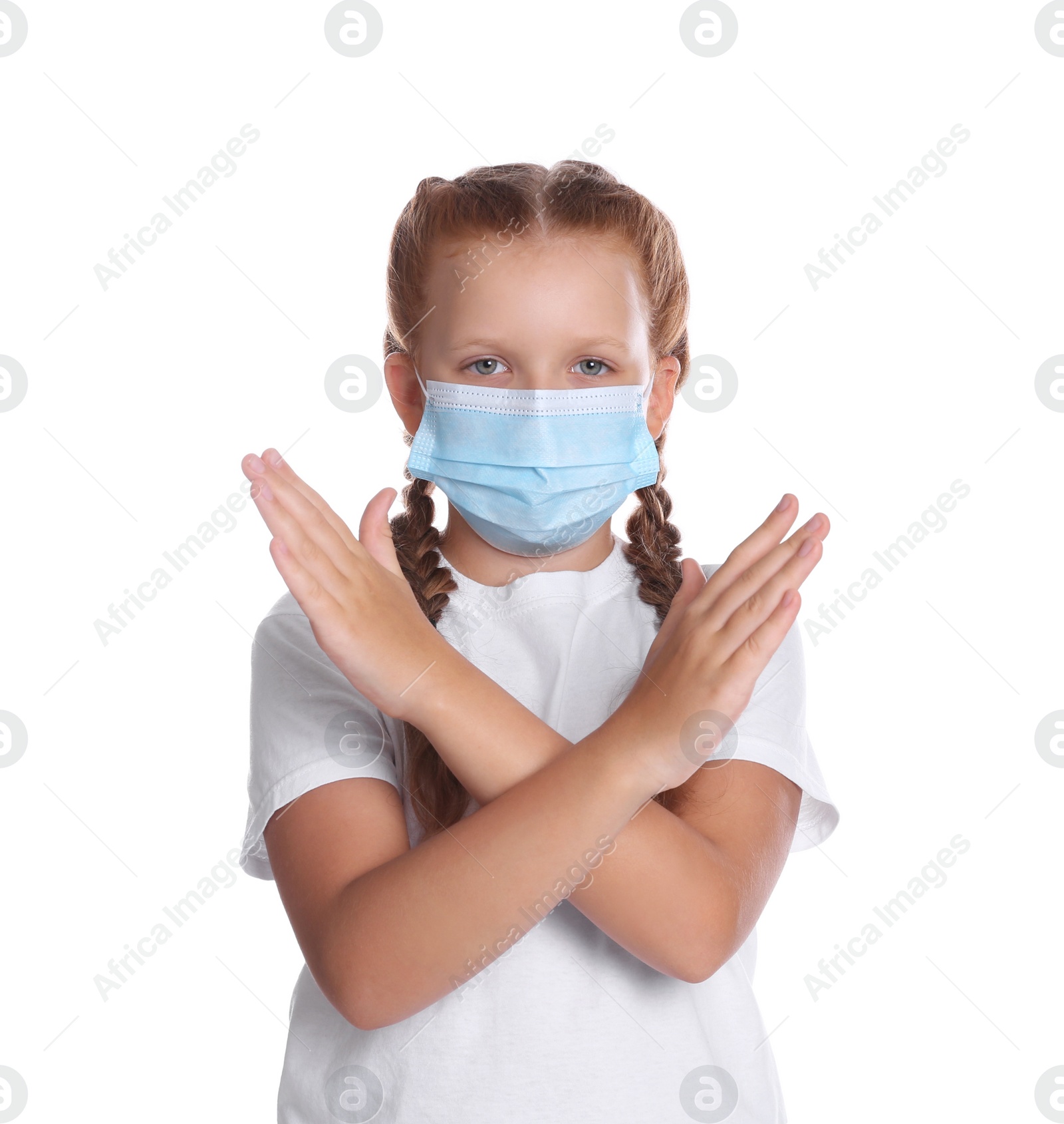 Photo of Little girl in protective mask showing stop gesture on white background. Prevent spreading of coronavirus