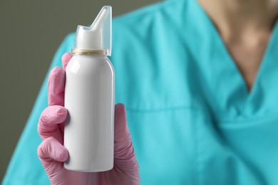Woman holding nasal spray bottle on olive background, closeup. Space for text