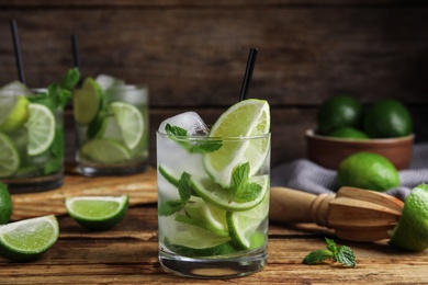Delicious mojito and ingredients on wooden table