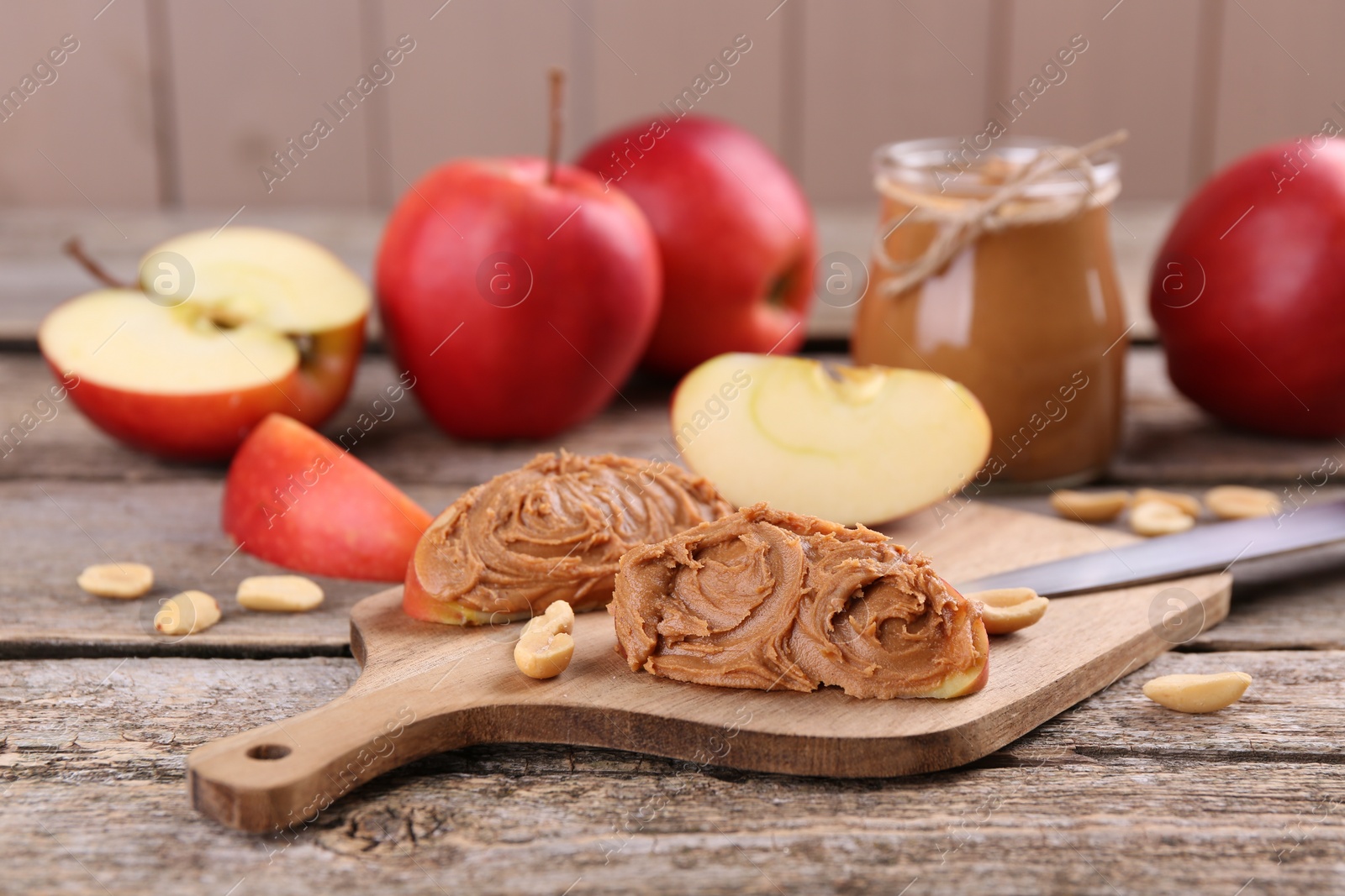 Photo of Fresh apples with peanut butter on wooden table