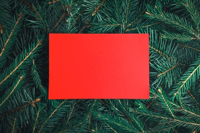 Photo of Blank card on Christmas tree branches as background, top view. Space for text