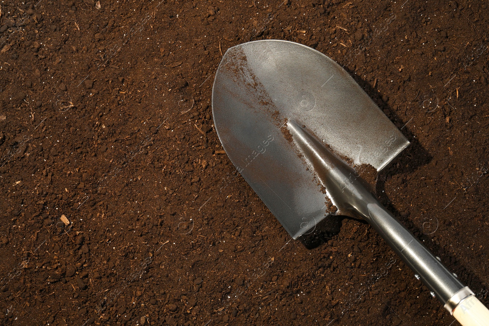 Metal shovel on fertile soil, top view and space for text. Gardening tool Photo of Metal shovel on fertile soil, top view and space for text. Gardening tool