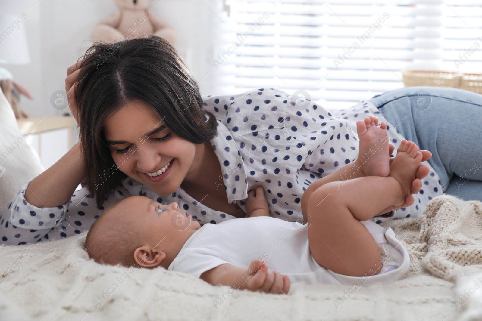 Photo of Mother with her cute baby on bed at home