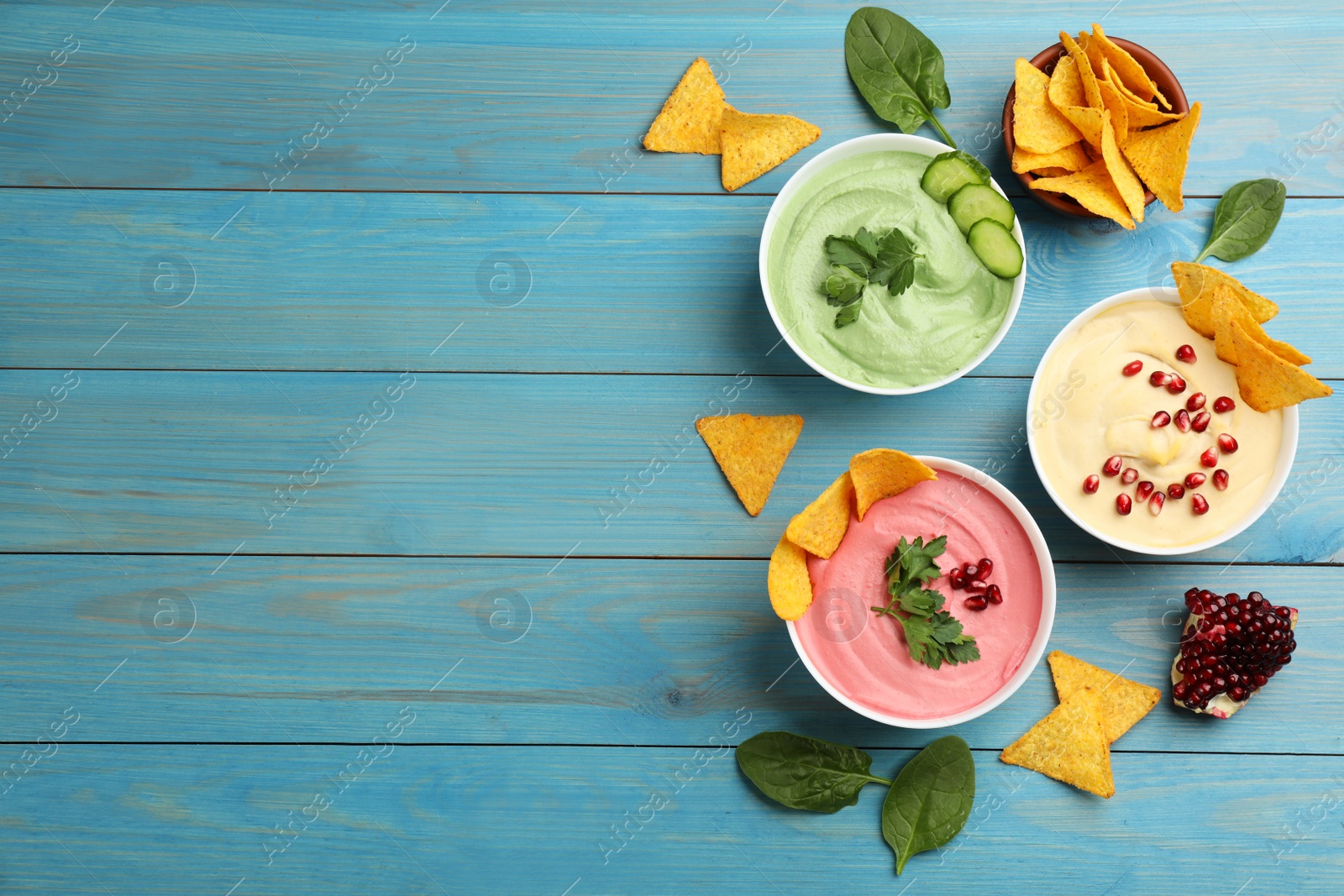 Photo of Flat lay composition with delicious hummuses on light blue wooden table. Space for text