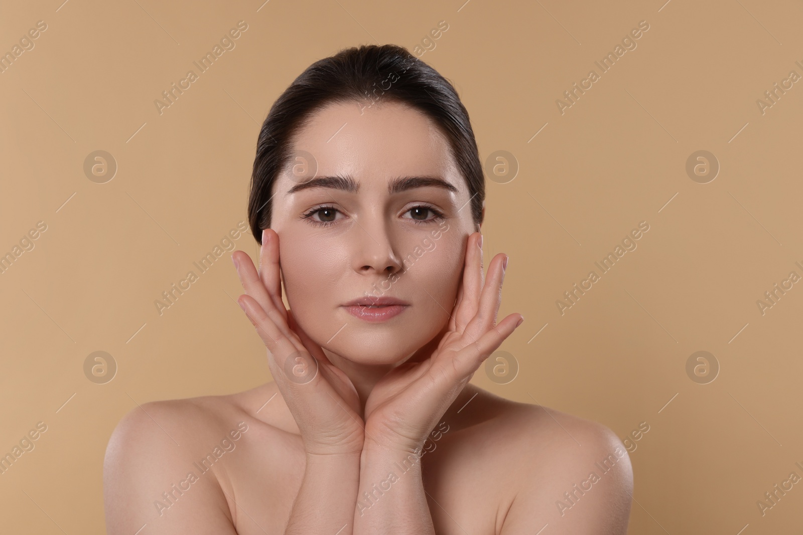 Photo of Young woman massaging her face on beige background