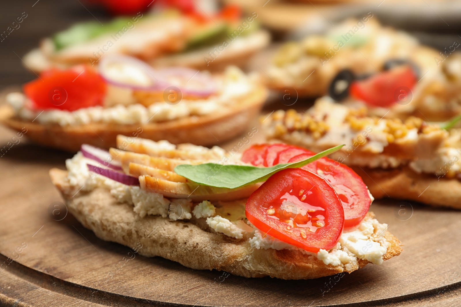 Photo of Delicious chicken bruschettas on wooden board, closeup