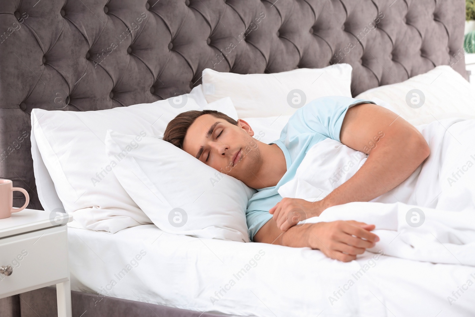 Photo of Young man sleeping on soft pillows in bed at home