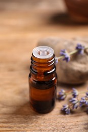 Photo of Bottle of essential oil and lavender flowers on wooden table, closeup
