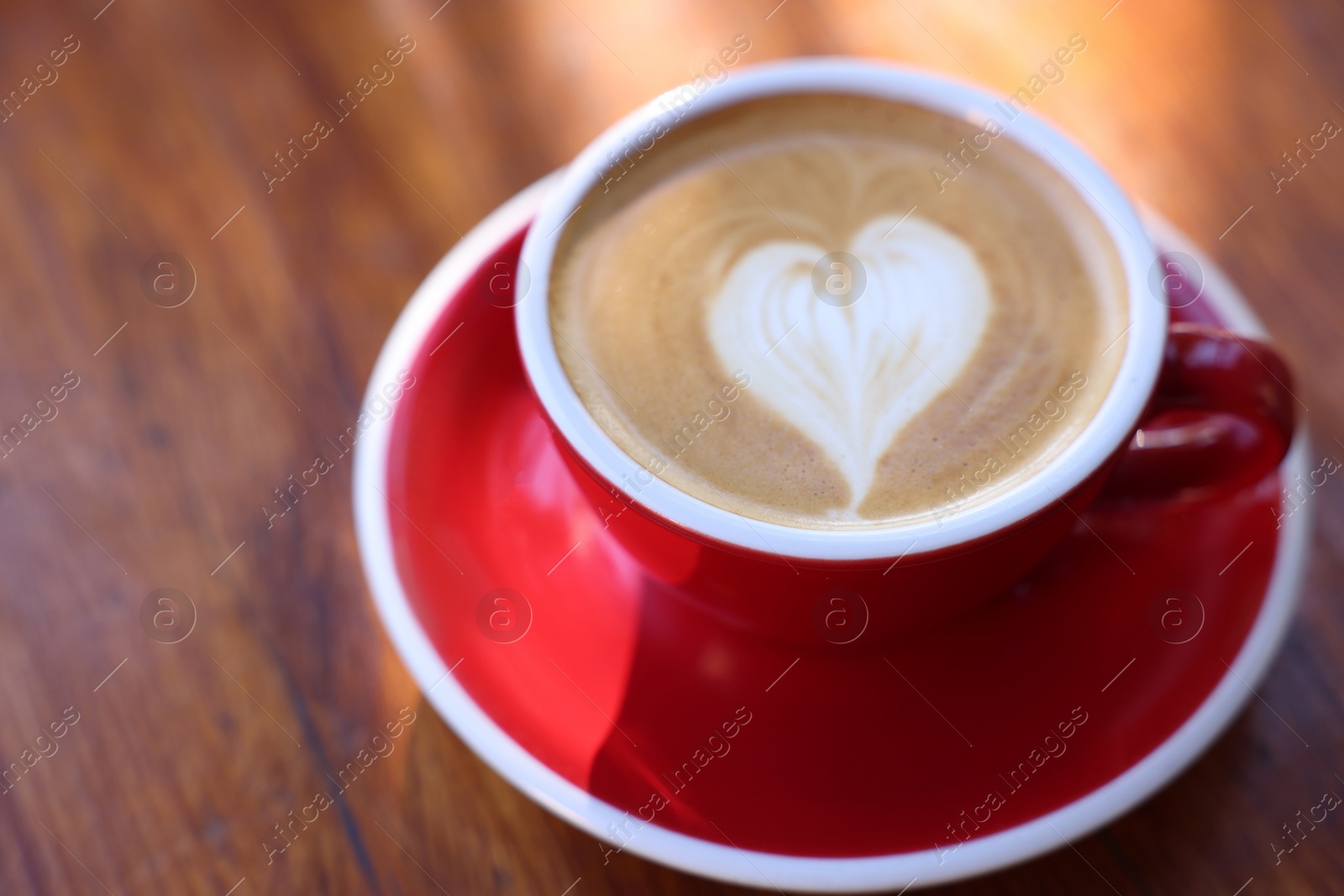 Photo of Cup of aromatic coffee with foam on wooden table, closeup. Space for text