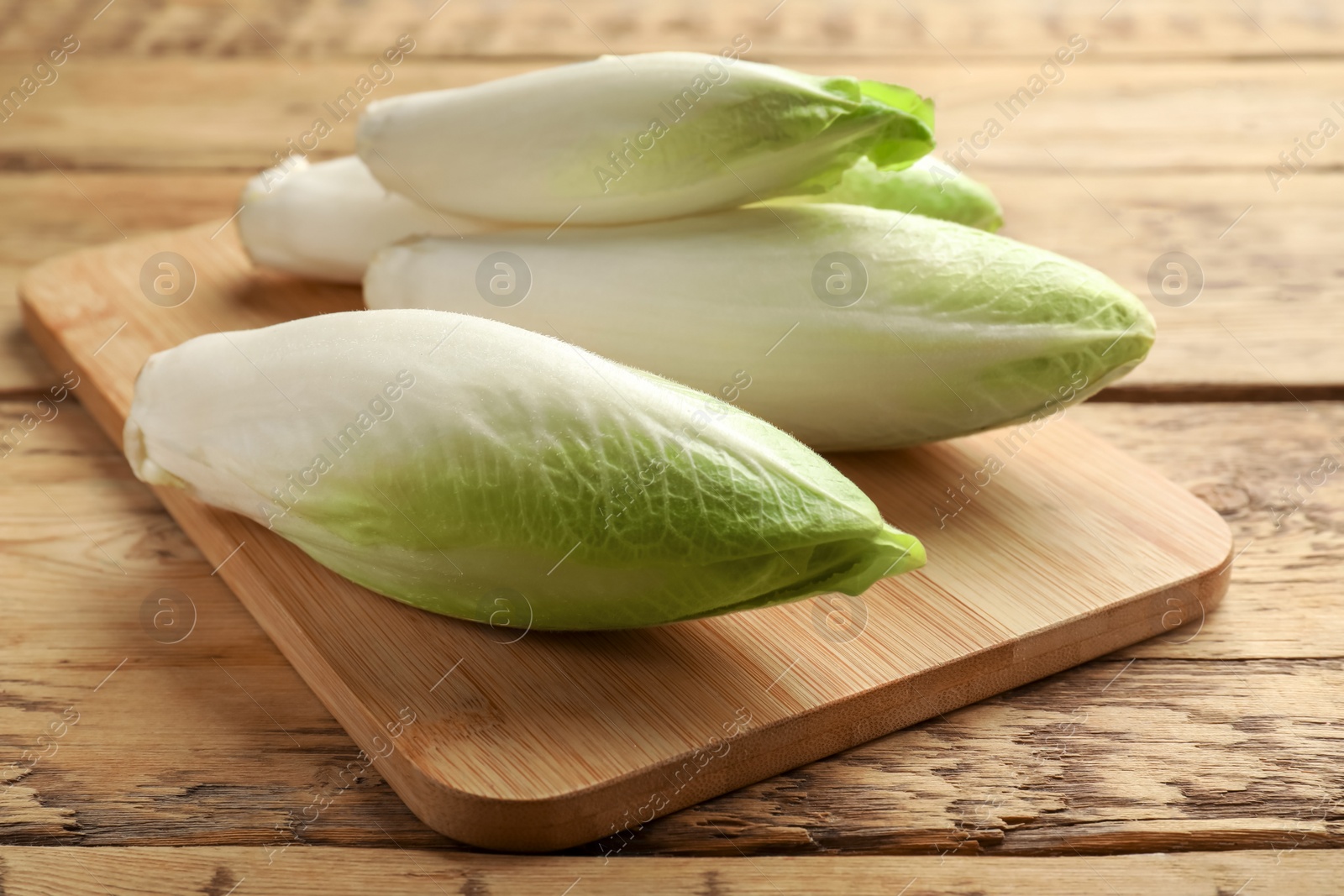 Photo of Fresh raw Belgian endives (chicory) on wooden table, closeup