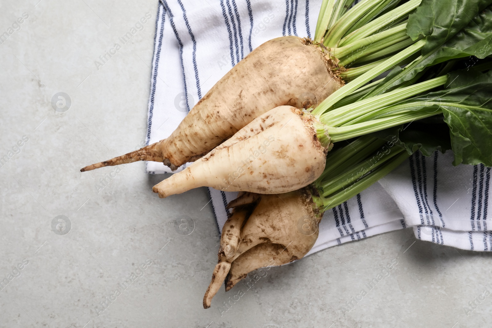 Photo of Fresh sugar beets with leaves on light grey table, flat lay