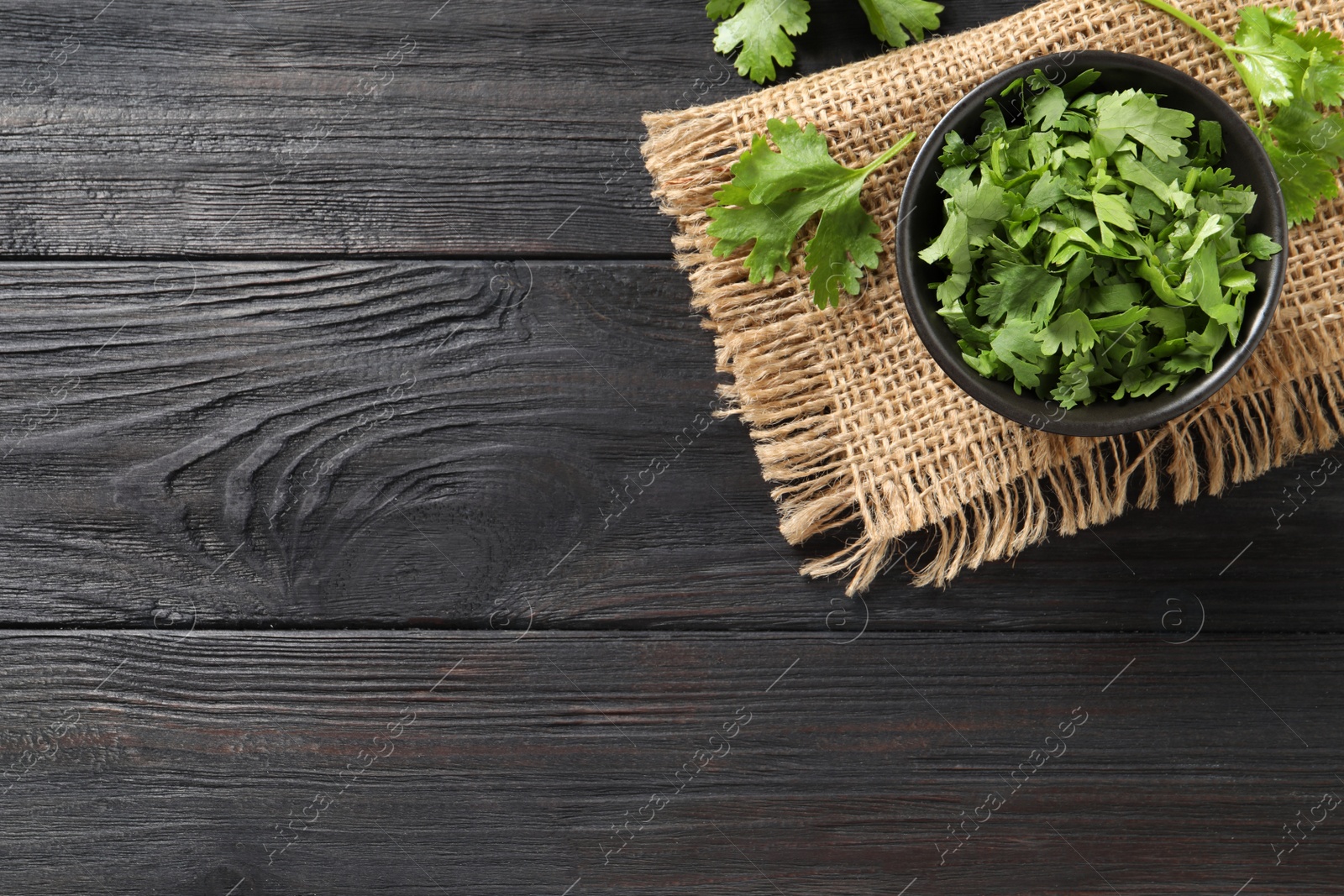 Photo of Fresh green cilantro on black wooden table, flat lay. Space for text