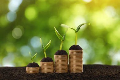 Image of Stacked coins and green seedlings on ground outdoors, bokeh effect. Investment concept