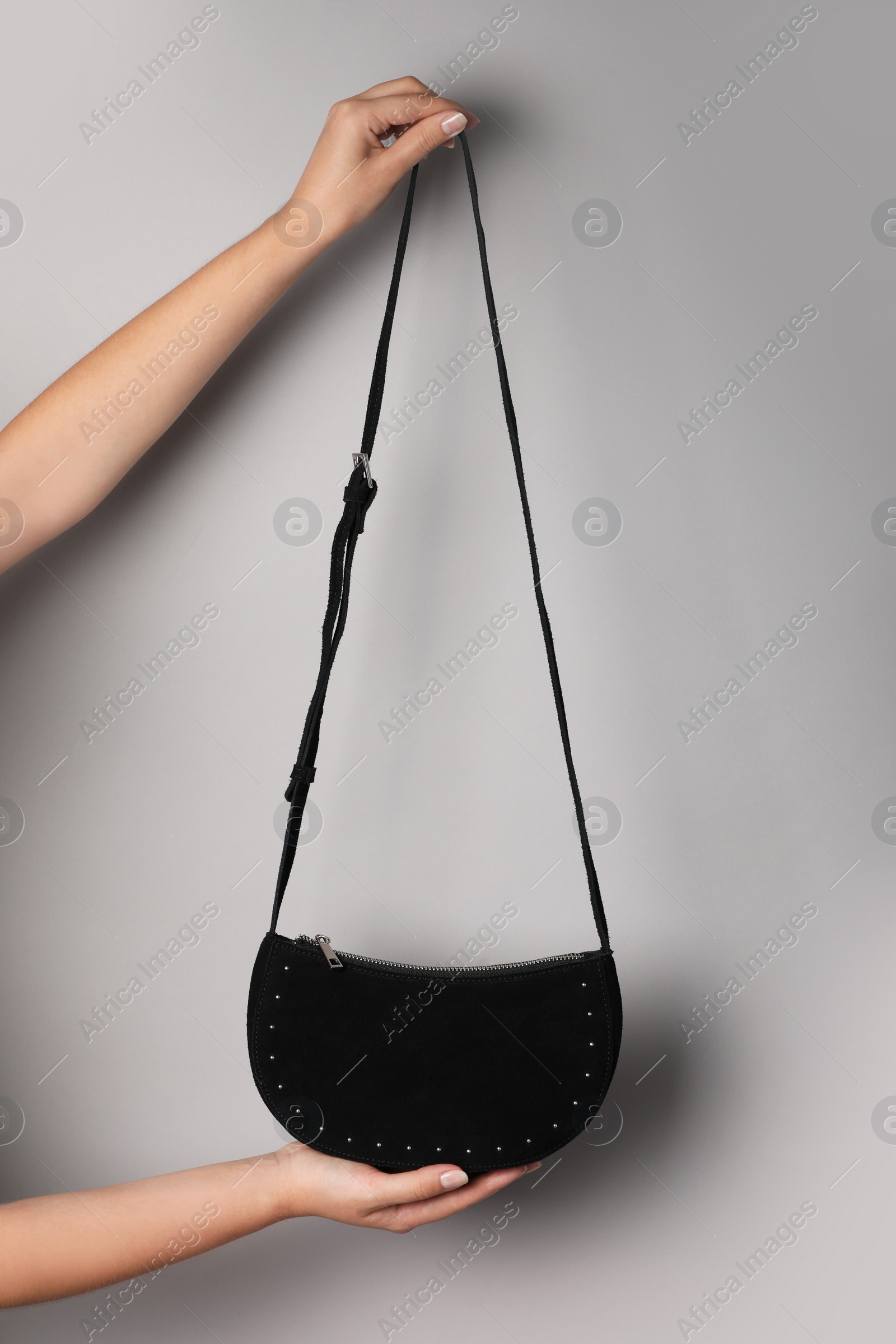 Photo of Woman holding stylish bag on light background, closeup