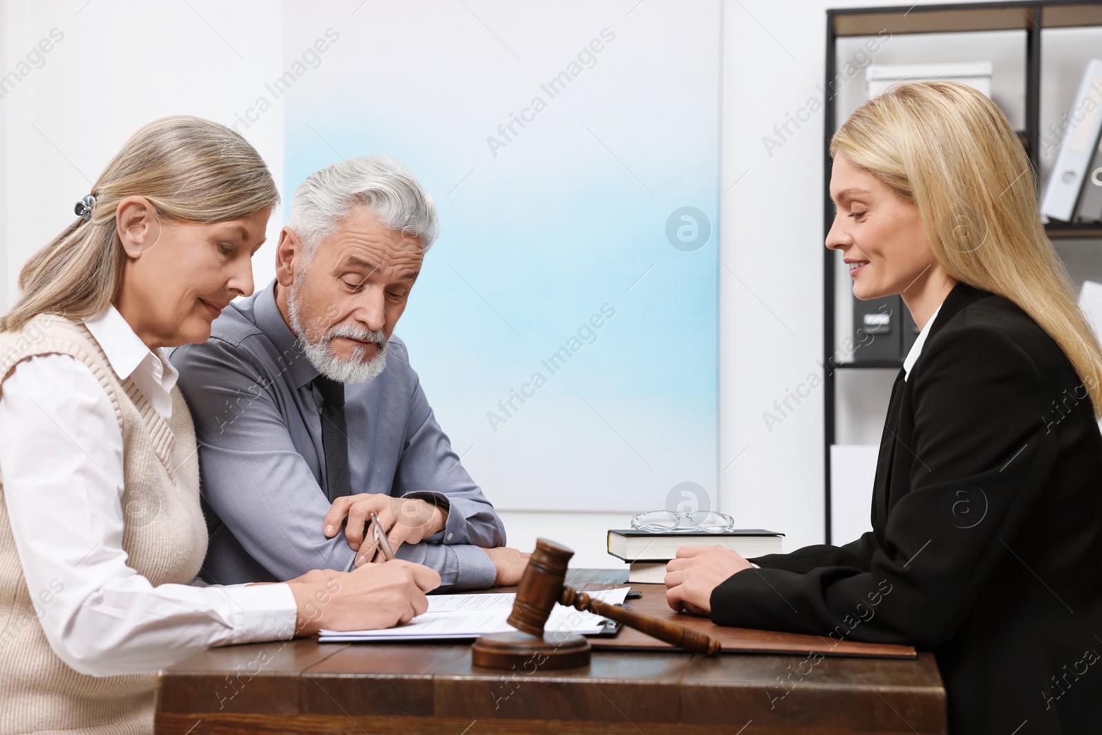 Photo of Senior couple signing document in lawyer's office