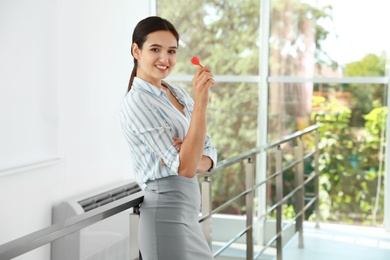 Photo of Happy young businesswoman with dart in office