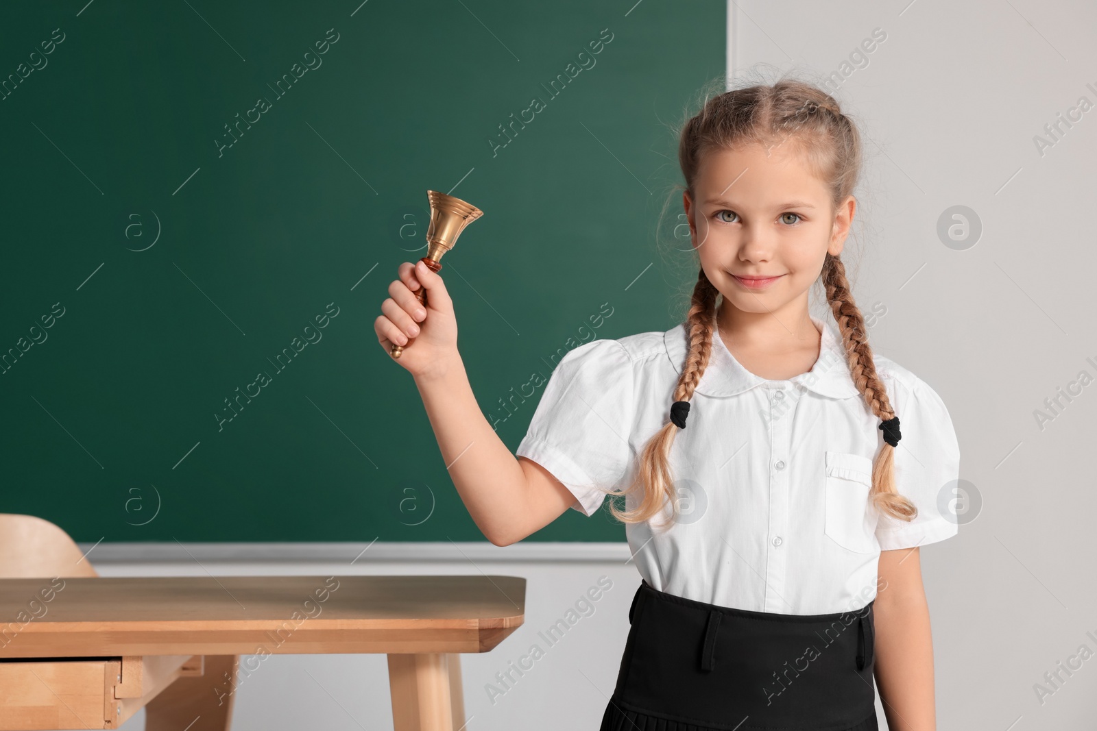 Photo of Pupil with school bell near chalkboard in classroom, space for text