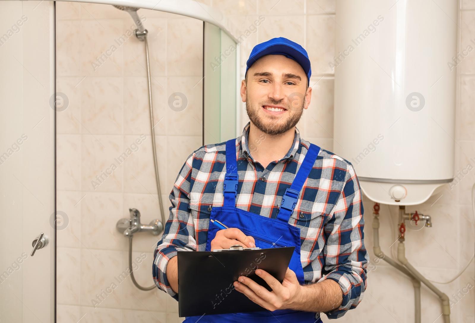 Photo of Professional plumber in uniform with clipboard indoors