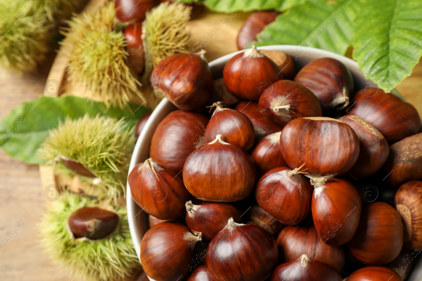 Photo of Fresh sweet edible chestnuts in bowl on table, top view