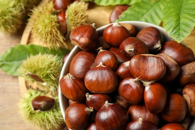 Fresh sweet edible chestnuts in bowl on table, top view