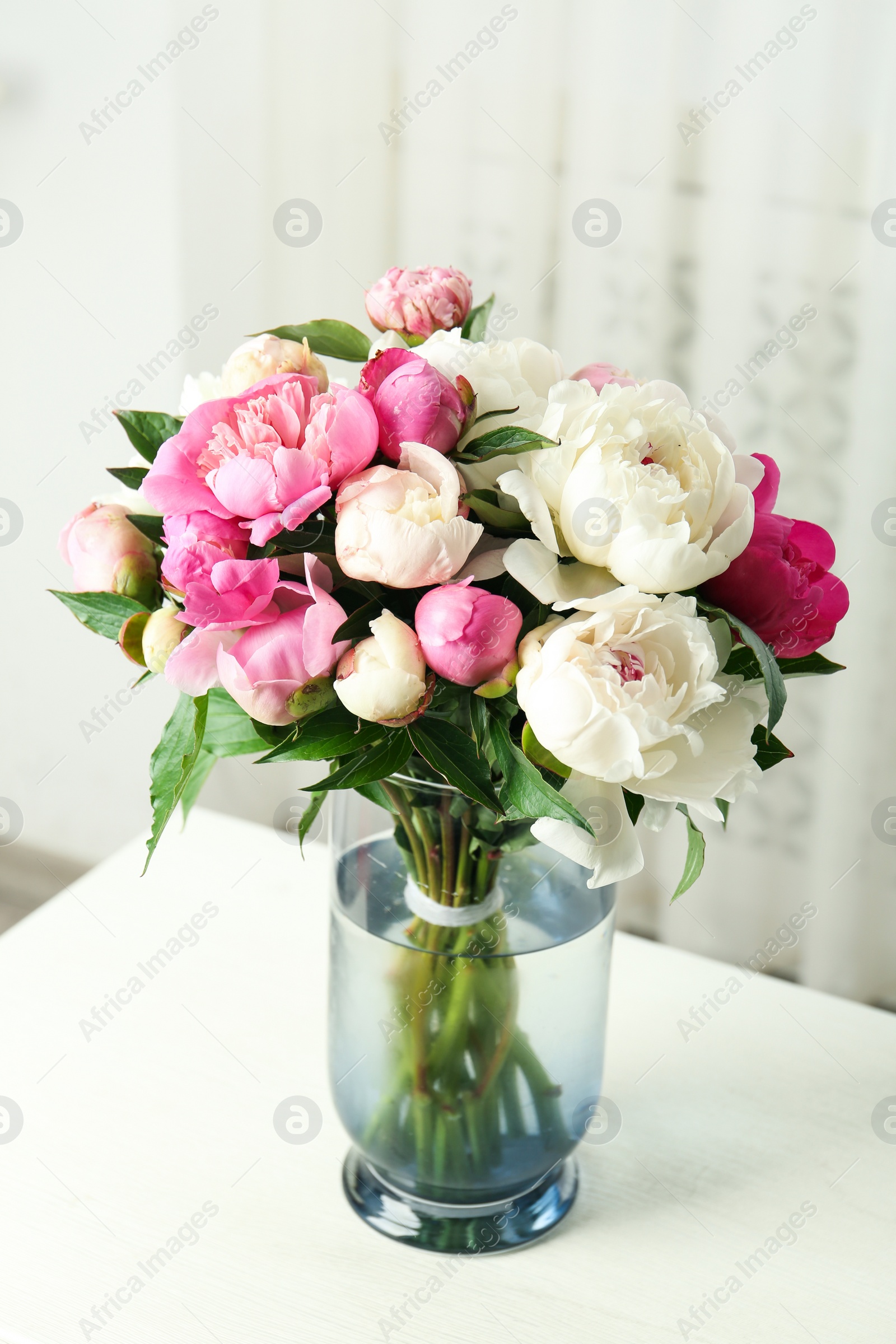 Photo of Bouquet of beautiful peonies in vase on white table