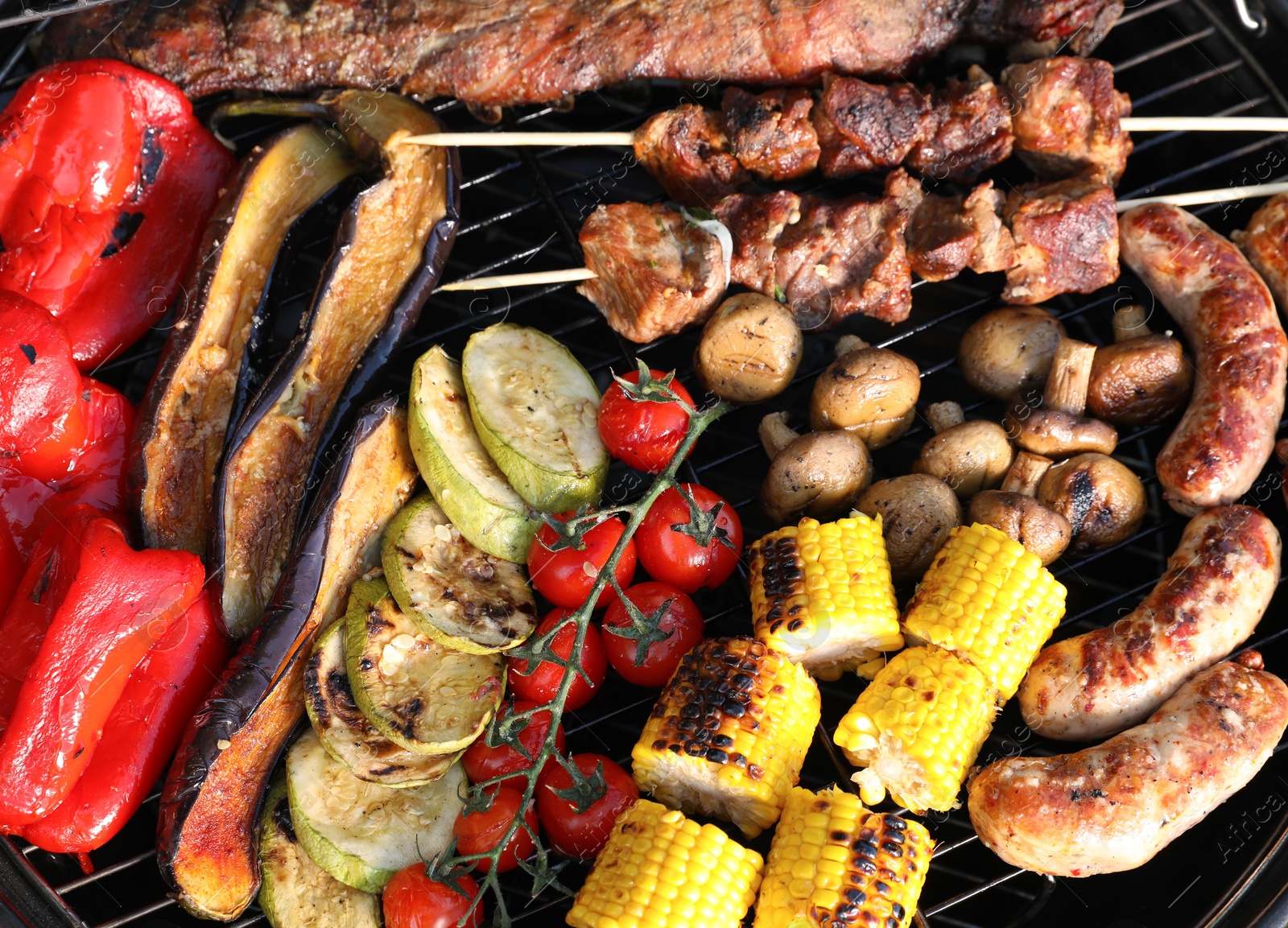 Photo of Tasty meat and vegetables on barbecue grill outdoors, top view