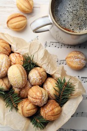 Photo of Homemade walnut shaped cookies with powdered sugar and fir branches in box on white wooden table, flat lay
