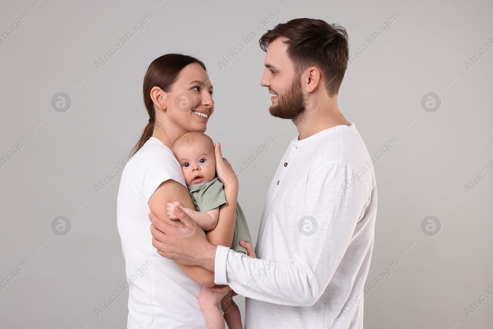 Photo of Happy family. Parents with their cute baby on grey background