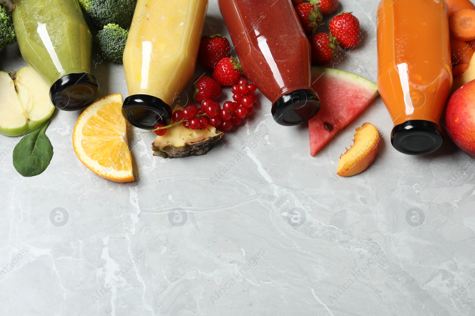 Photo of Bottles of delicious juices and fresh fruits on marble table. Space for text