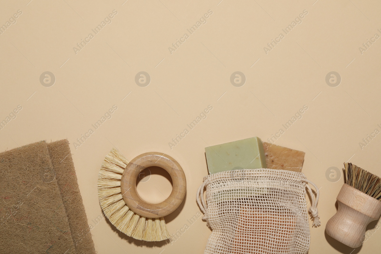 Photo of Cleaning brushes, soap bars and sponges on beige background, flat lay. Space for text