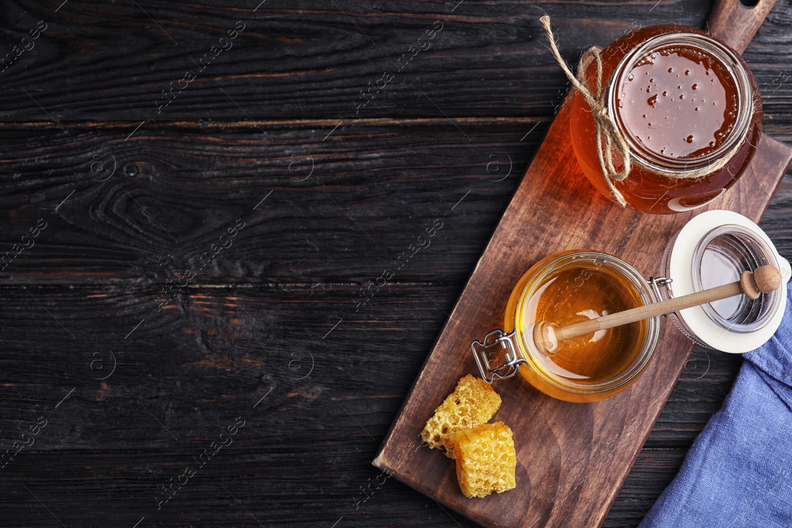 Photo of Flat lay composition with delicious honey on black wooden table. Space for text