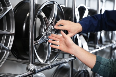 Photo of Service center consultant and customer near alloy wheels in store, closeup