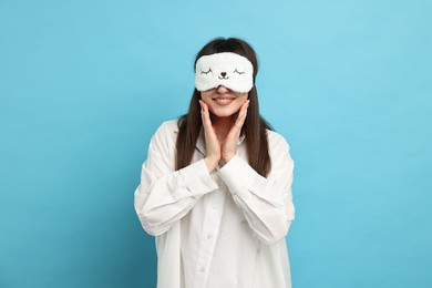 Photo of Woman in pyjama and sleep mask on light blue background