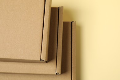 Photo of Many closed cardboard boxes on pale yellow background, above view. Space for text