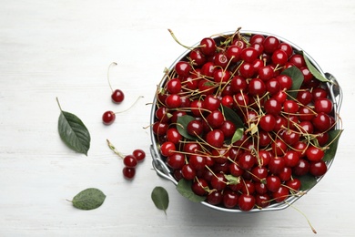 Bucket of delicious cherries on white wooden table, top view. Space for text