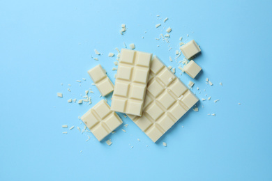 Tasty white chocolate on light blue background, flat lay