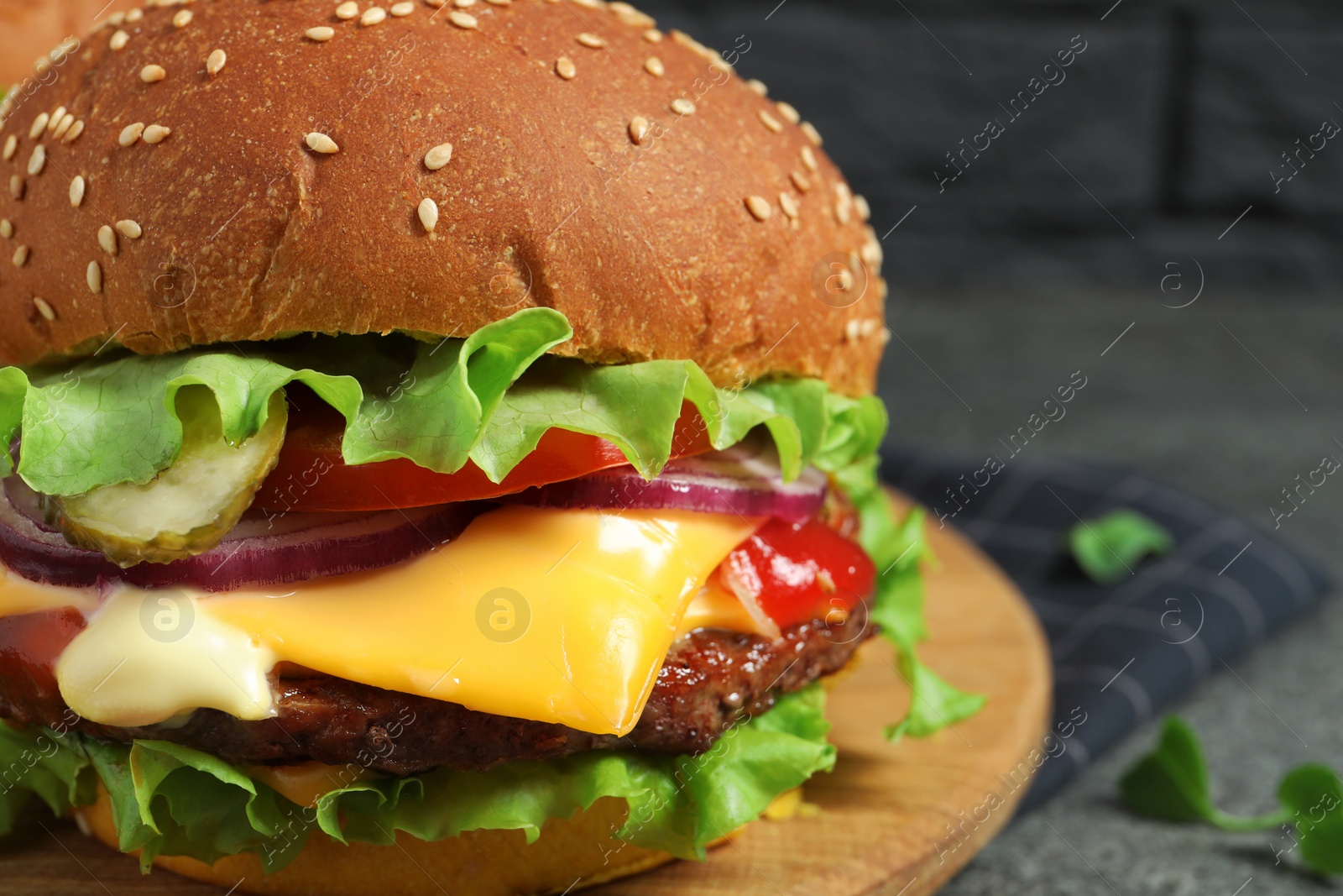 Photo of Delicious burger with beef patty and lettuce on grey table, closeup