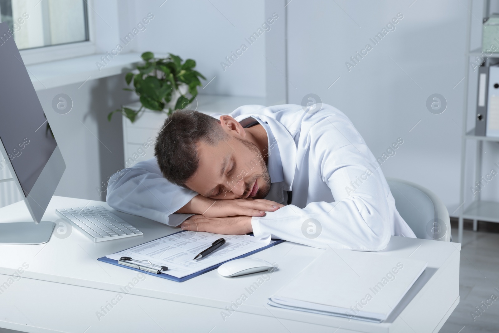 Photo of Exhausted doctor sleeping at workplace in hospital