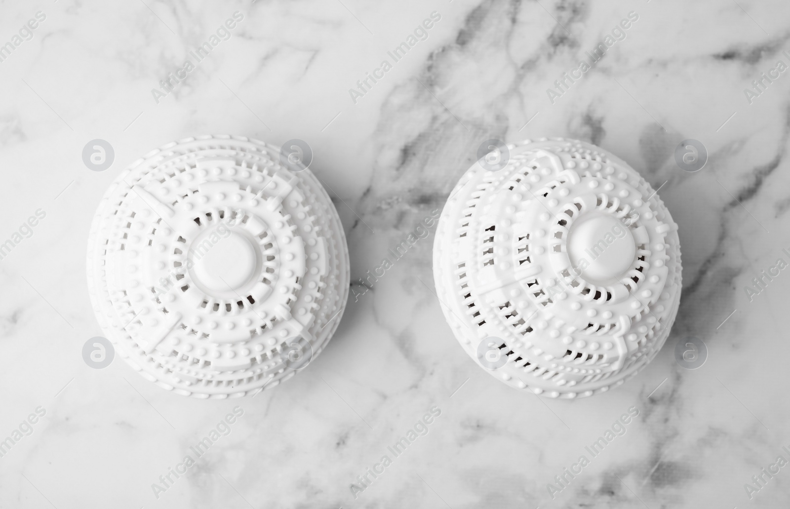 Photo of Dryer balls for washing machine on white marble table, flat lay