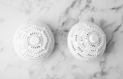 Photo of Dryer balls for washing machine on white marble table, flat lay