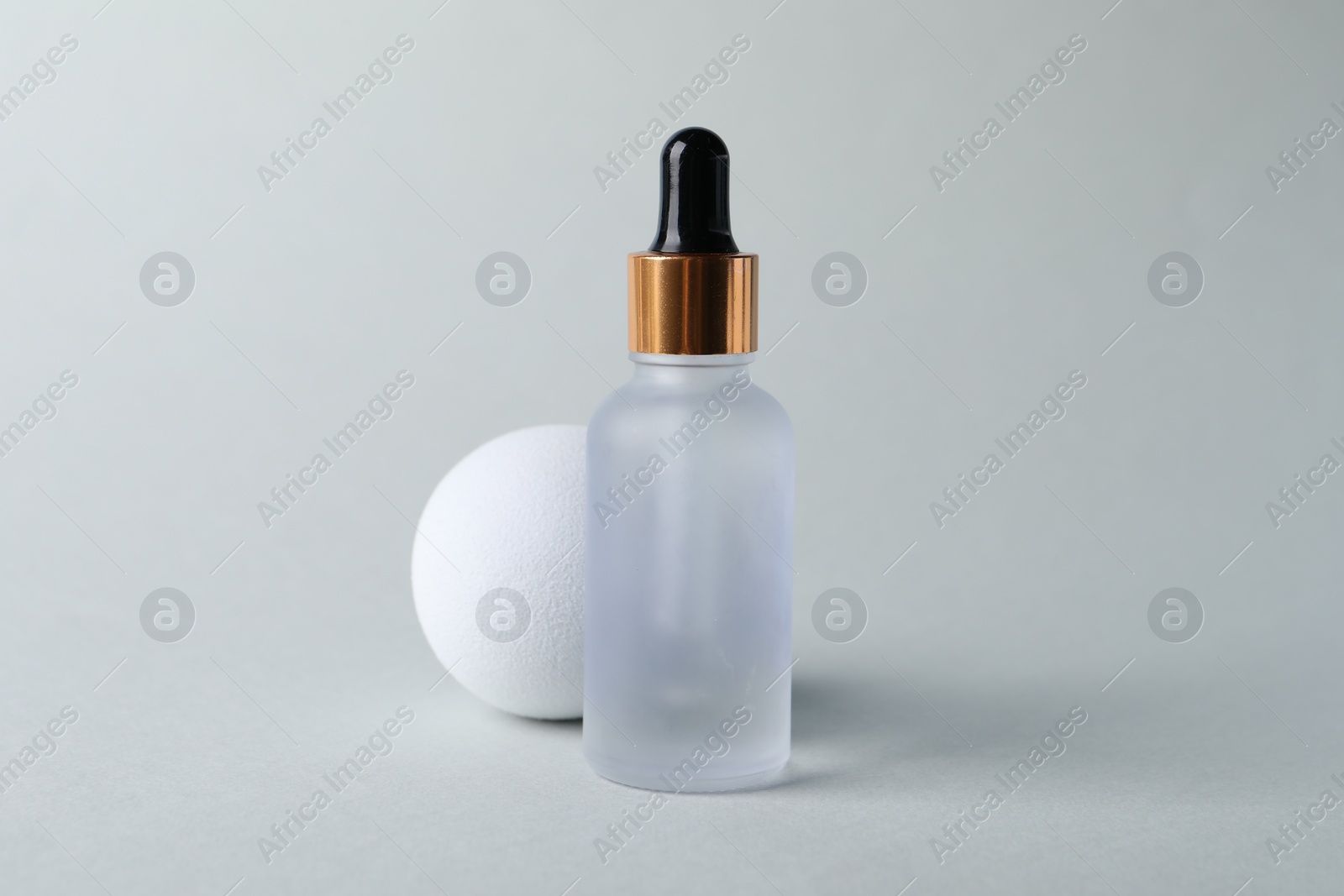 Photo of Bottle with cosmetic serum on light grey background