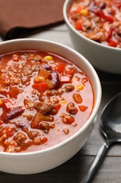 Tasty chili con carne served on wooden table, closeup