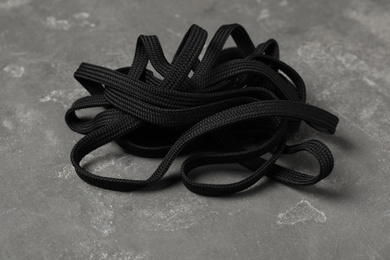 Photo of Black shoelace on grey stone background. Stylish accessory