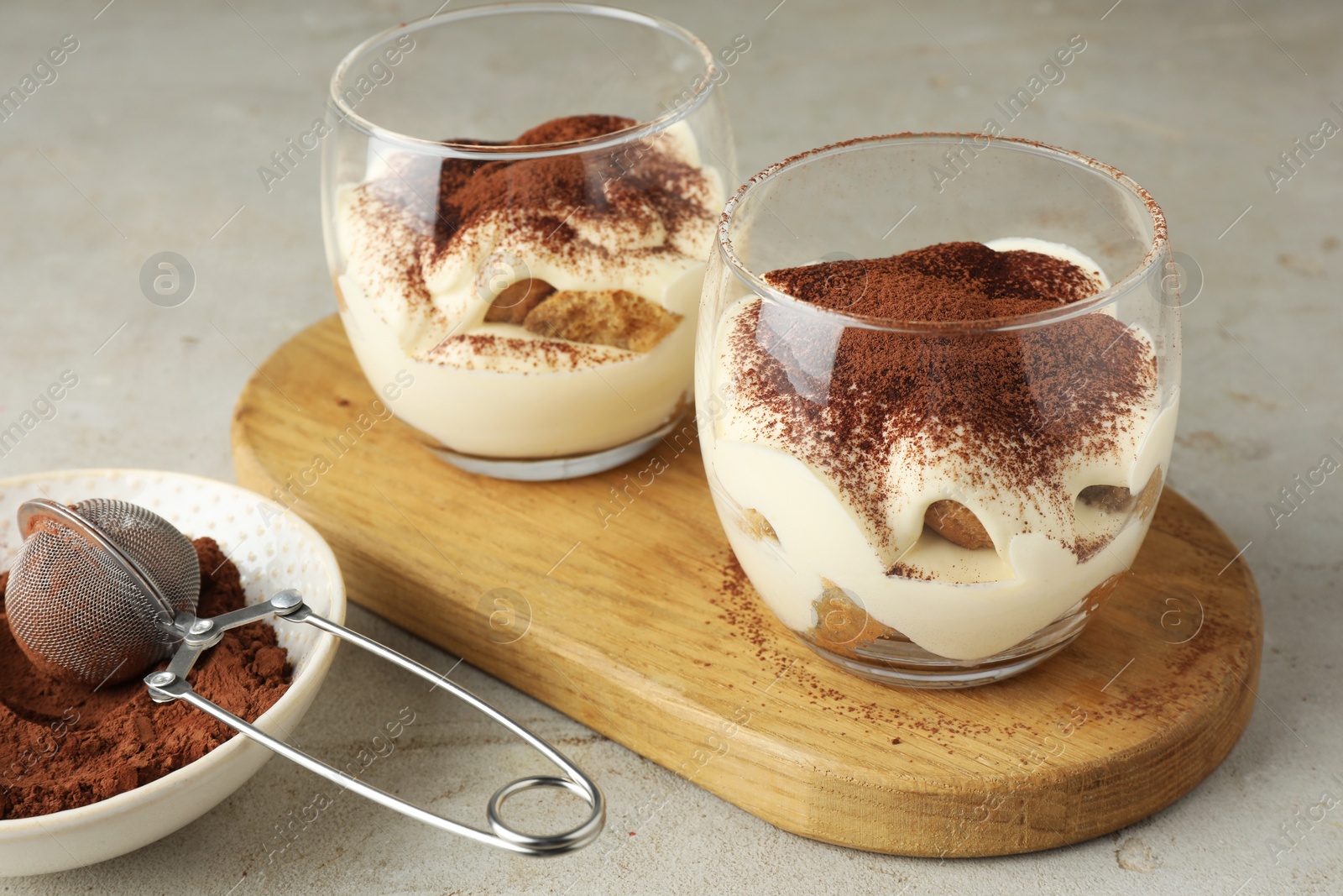 Photo of Delicious tiramisu in glasses on light table