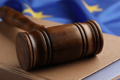 Wooden judge's gavel and book on flag of European Union, closeup