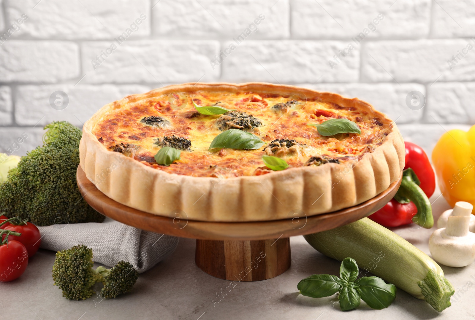 Photo of Delicious homemade vegetable quiche and ingredients on table