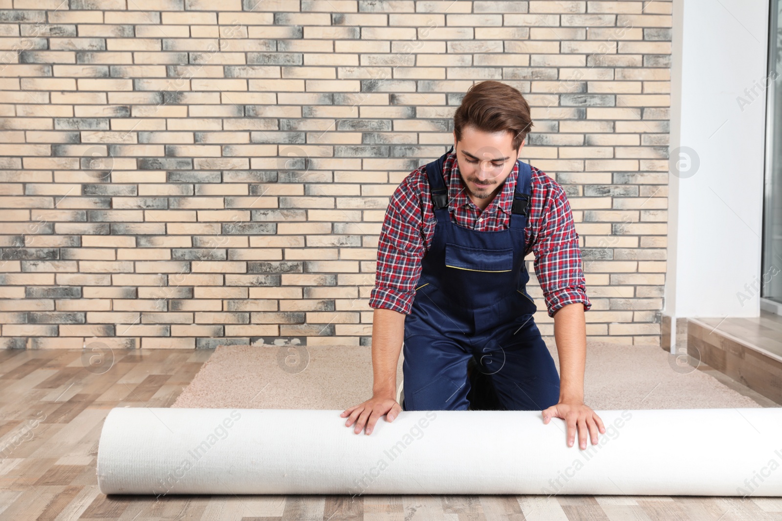 Photo of Man rolling out new carpet flooring indoors