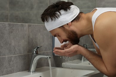 Man with headband washing his face in bathroom