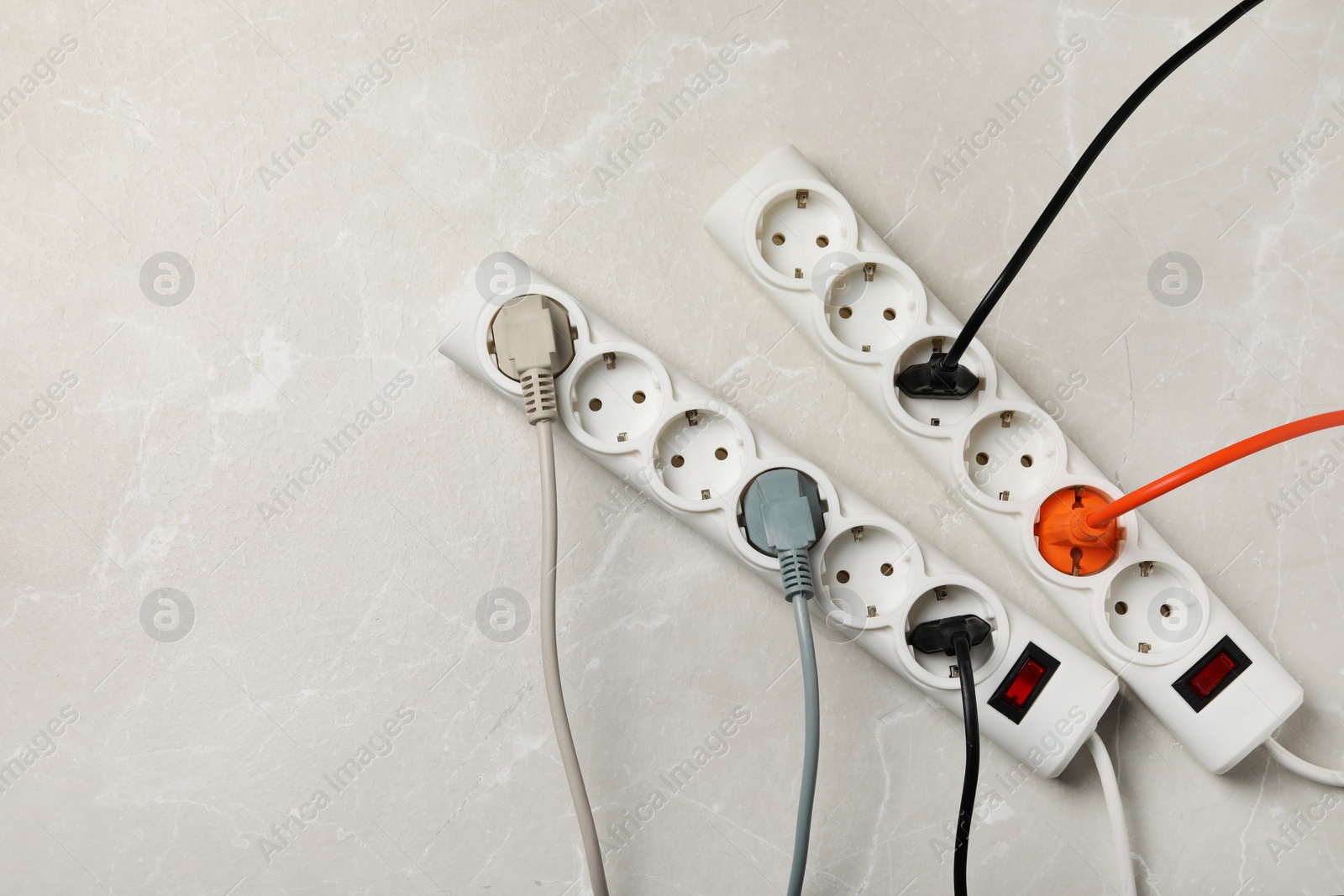 Photo of Power strip with extension cords on grey marble table, flat lay. Space for text